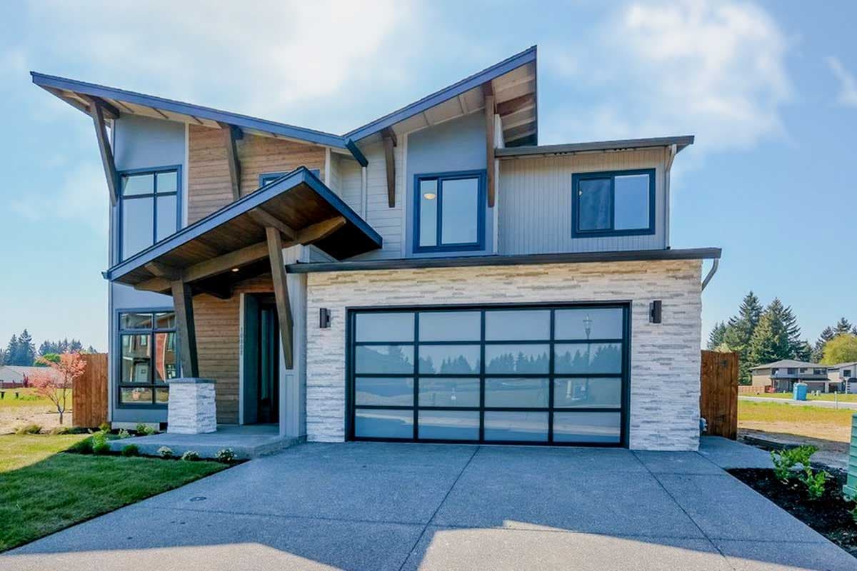 Modern house plan exterior with asymmetric gables, wood siding, stone facade, and glass garage door.