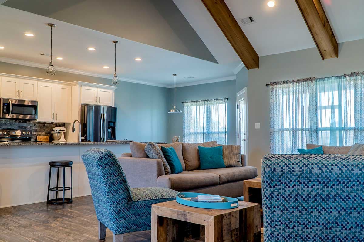 Open concept living area with kitchen, island, living room with coffered ceiling and decorative beams.
