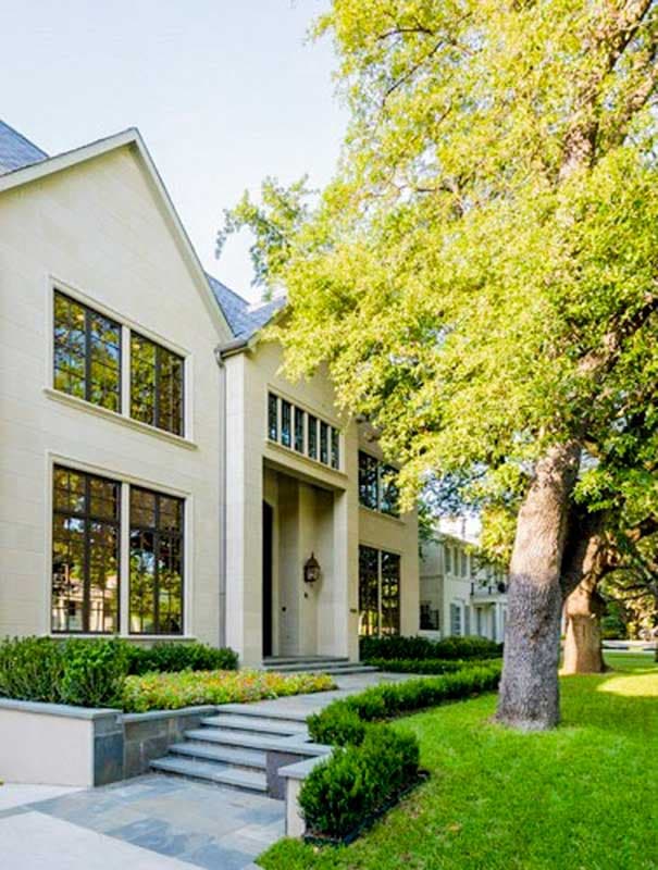 Two-story modern house plan exterior with stone facade, large windows, deep-set entrance, and manicured landscaping.