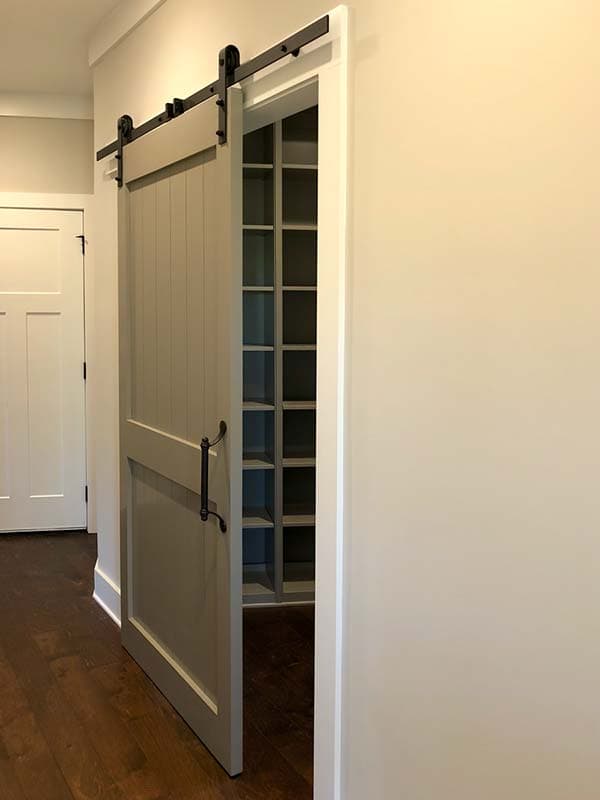 Interior view of a pantry with gray shelving and a gray sliding barn door with black hardware.