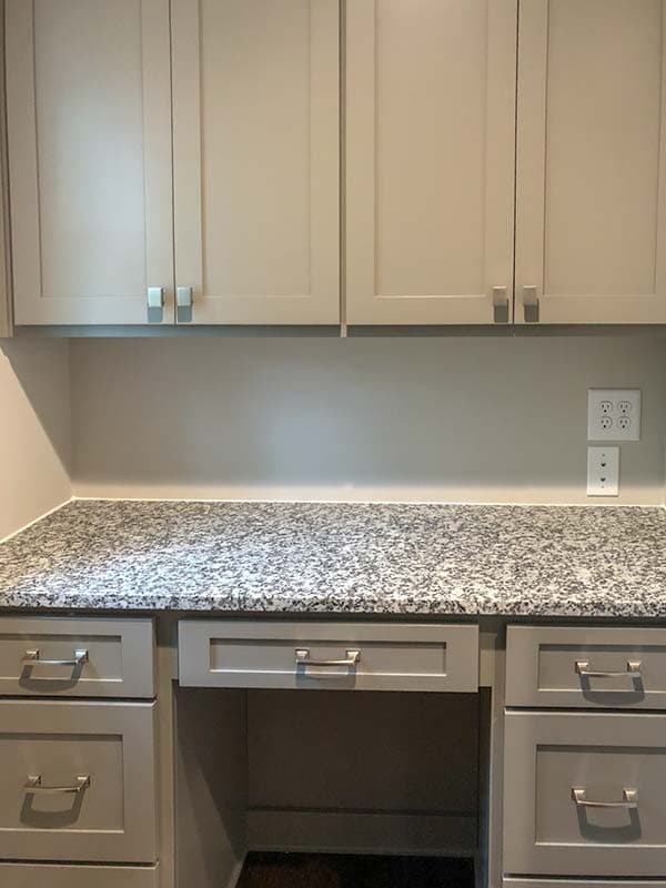 Built-in desk with gray shaker cabinets, granite countertop, and brushed nickel hardware.