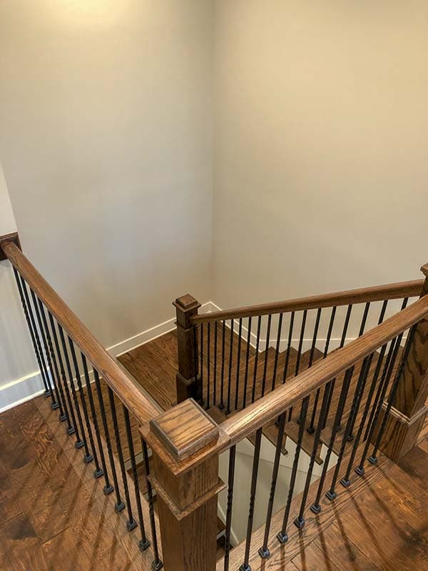 Interior view of a wooden staircase with black balusters and a landing.