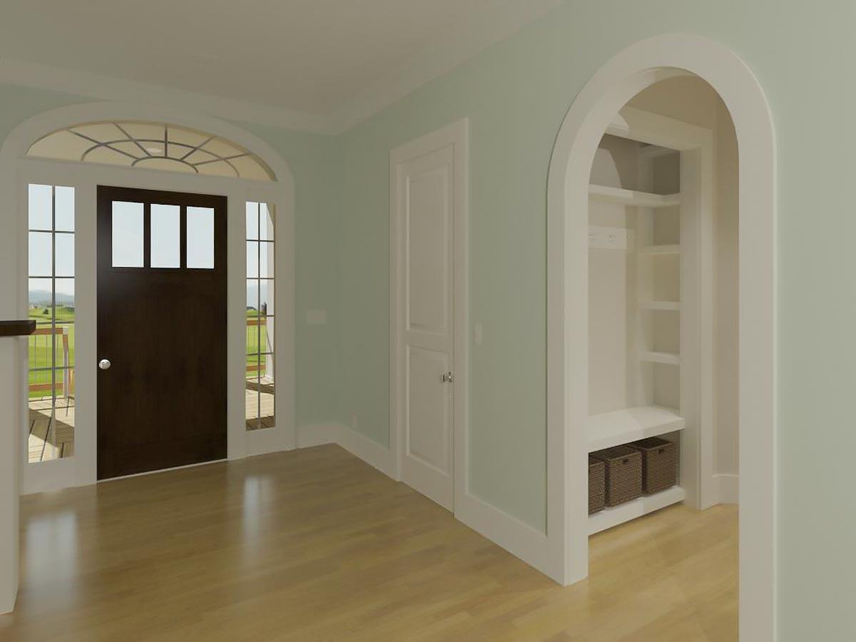 Interior view of a house entrance with a dark wood door, arched transom window, side windows, and a built-in arched alcove with shelving and baskets.