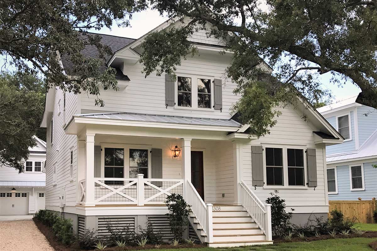 House plan exterior featuring a two-story Craftsman style home with porch, gables, and gray shutters. The home has a dark roof and white siding.