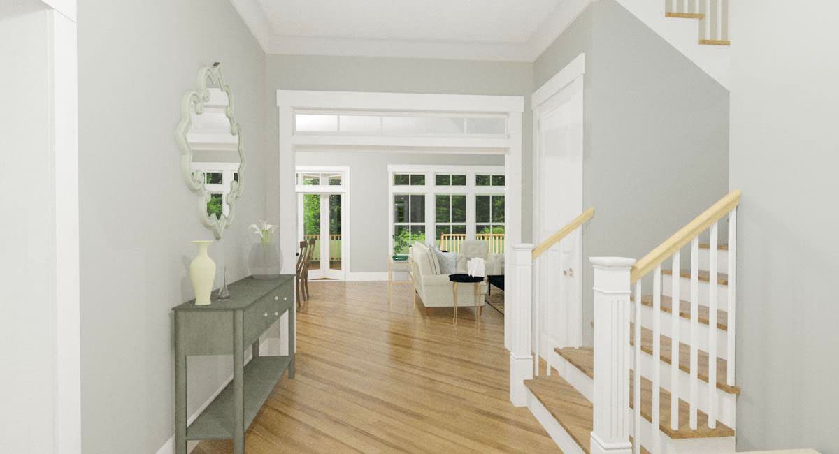 Interior view of a house entry with a console table, staircase, and view into a living area with large windows.
