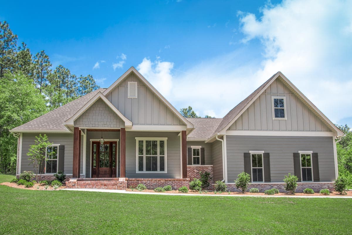 House plan exterior. One-story Ranch style home with gables, a covered front porch, and brick foundation details.