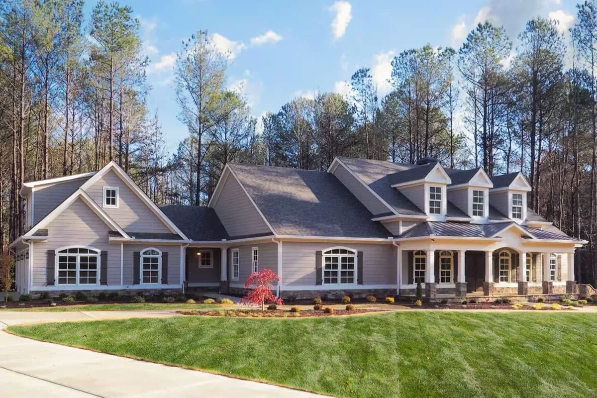 House plan exterior. Two-story, with gabled roofline, dormers, and front porch with columns. Features include shutters and attached garage.