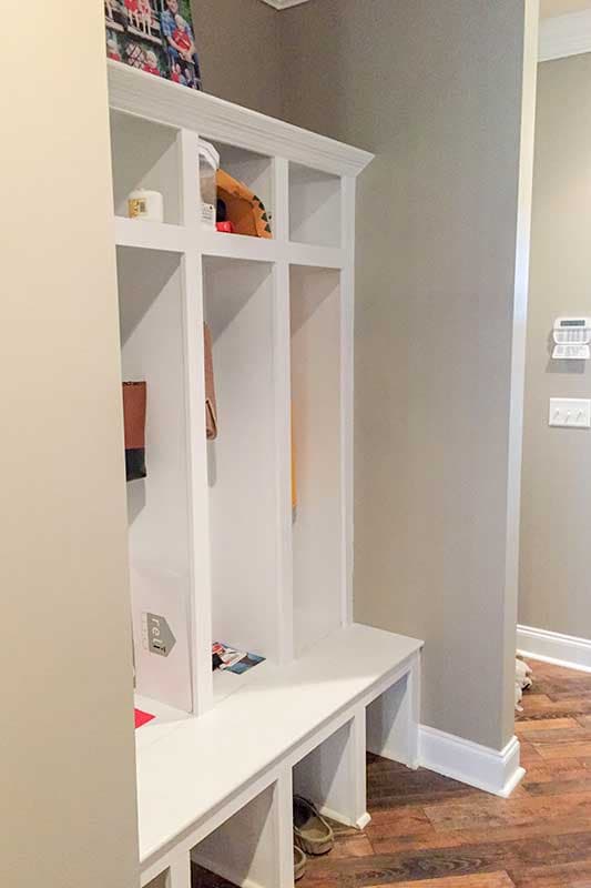 Built-in white mudroom bench with cubbies for storage, with a picture displayed above.