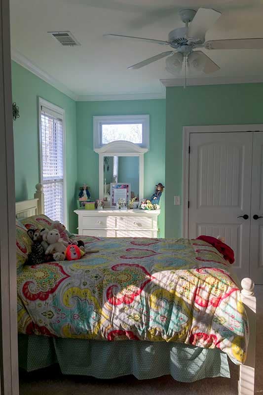 Bedroom interior with bed, dresser, closet, and window. Ceiling fan visible.