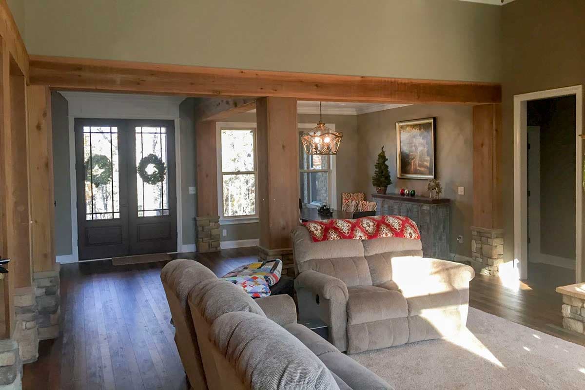 Interior view of a living area with double doors, exposed wood beams, stone accents, and seating.