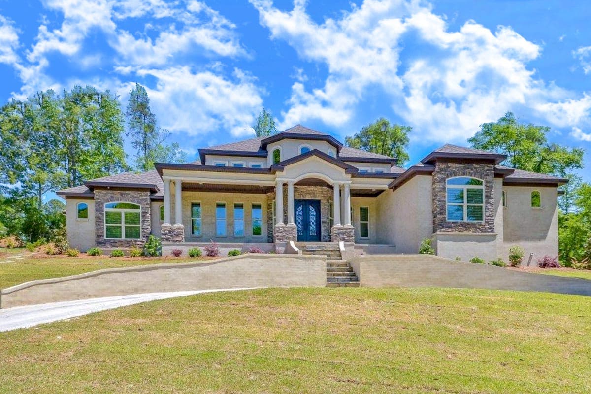 House plan exterior with a covered entry, stone accents, multiple gables, and a stepped roofline.
