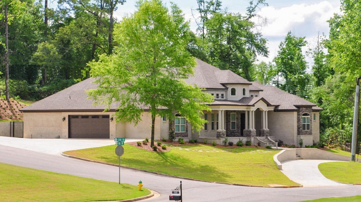 House plan exterior: A one-story Modern house with a side-entry garage, covered front porch with columns, and arched window details.