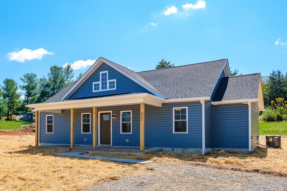 House plan exterior. Ranch style with a front porch, gable roof, and decorative gable window. Features a blue-sided exterior and a single story.