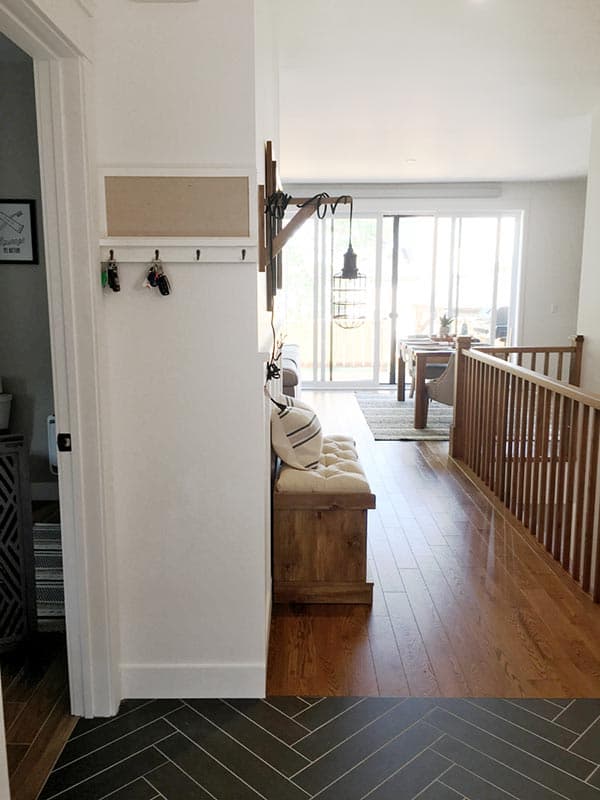 Hallway interior with wood bench, key hooks, and view to dining area with sliding glass doors.