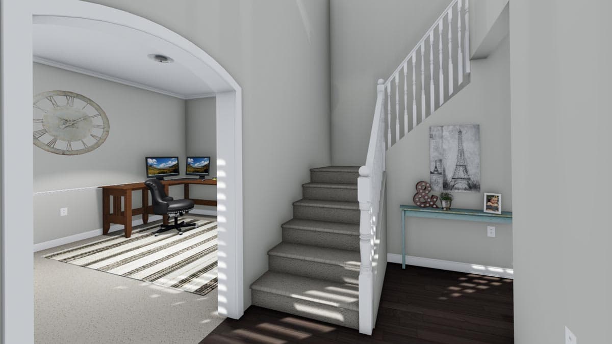 Interior view of a home entry showing a staircase, office area with desks and computers, and a console table with decor.