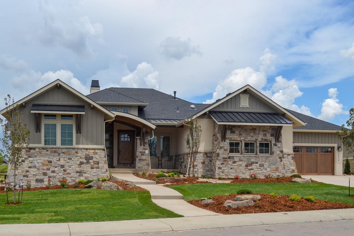 House plan exterior: Modern home with stone base, board and batten siding, prominent gables, and a covered entry.