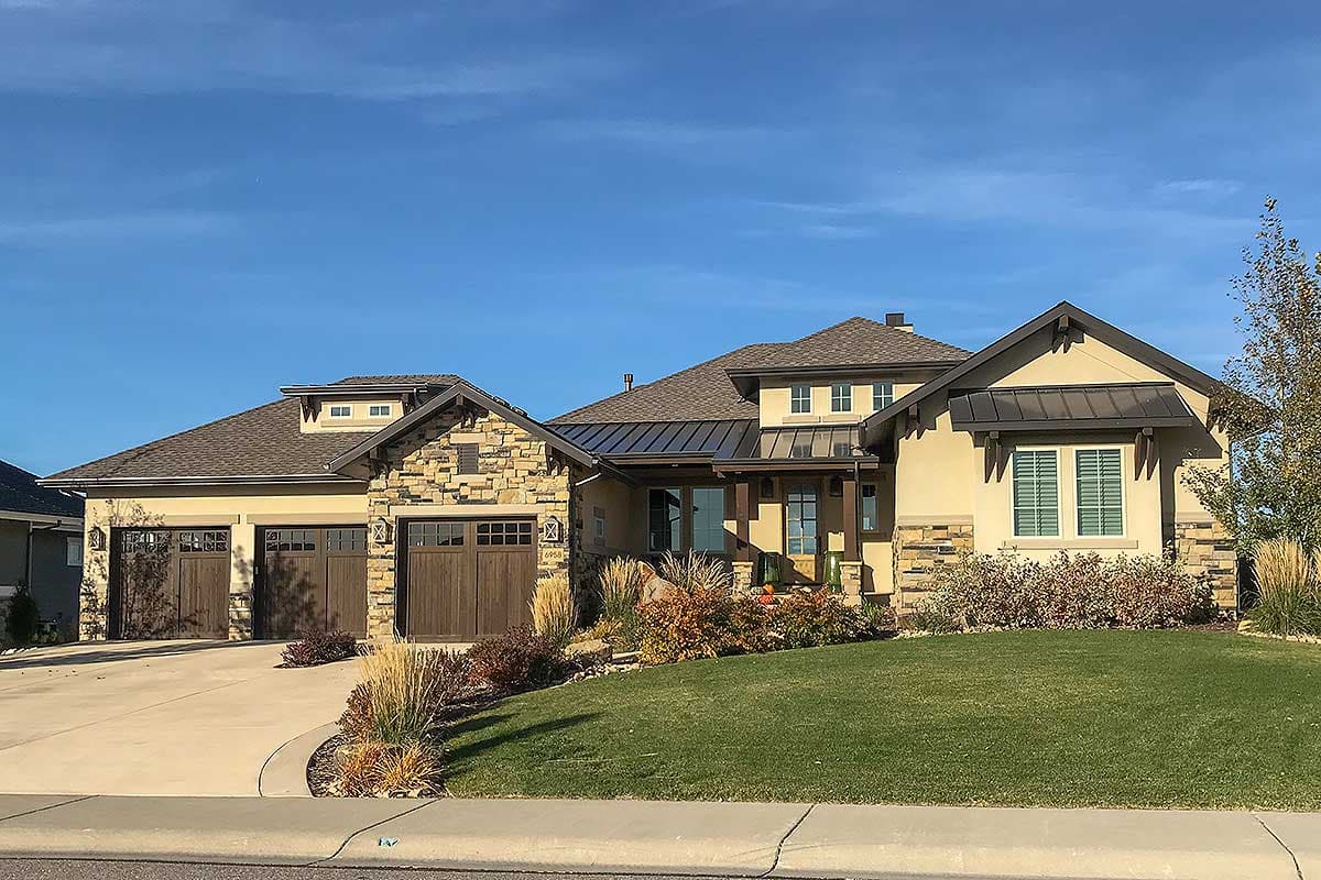 House plan exterior with stone accents, a multi-level roofline, dormers, and a three-car garage.