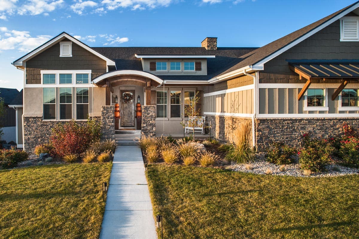 House plan exterior featuring a Craftsman style. The home has a gabled roof, stone veneer, and an arched entryway with wood columns.