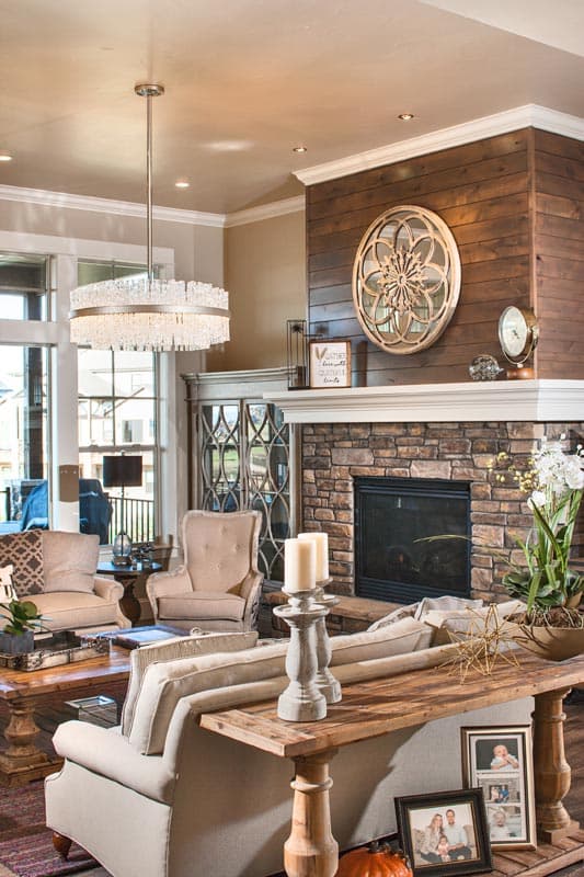 Living room with stone fireplace, wood accent wall, seating, and chandelier.