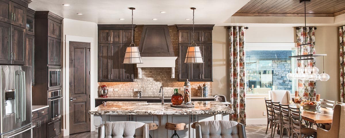 Kitchen with dark wood cabinets, a brick backsplash, granite island, and adjacent dining area with a rustic chandelier.