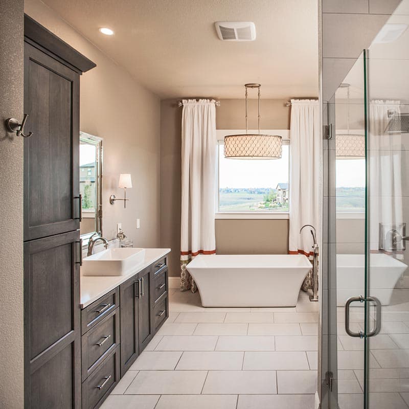 Modern bathroom with freestanding tub, glass-enclosed shower, double vanity with vessel sink, and tall dark wood cabinetry.
