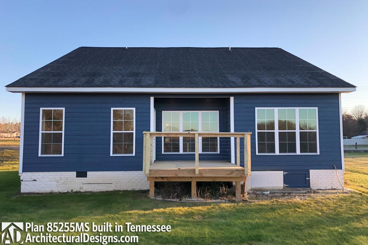 House plan exterior: single-story home with blue siding, white-trimmed windows, and a wooden deck.
