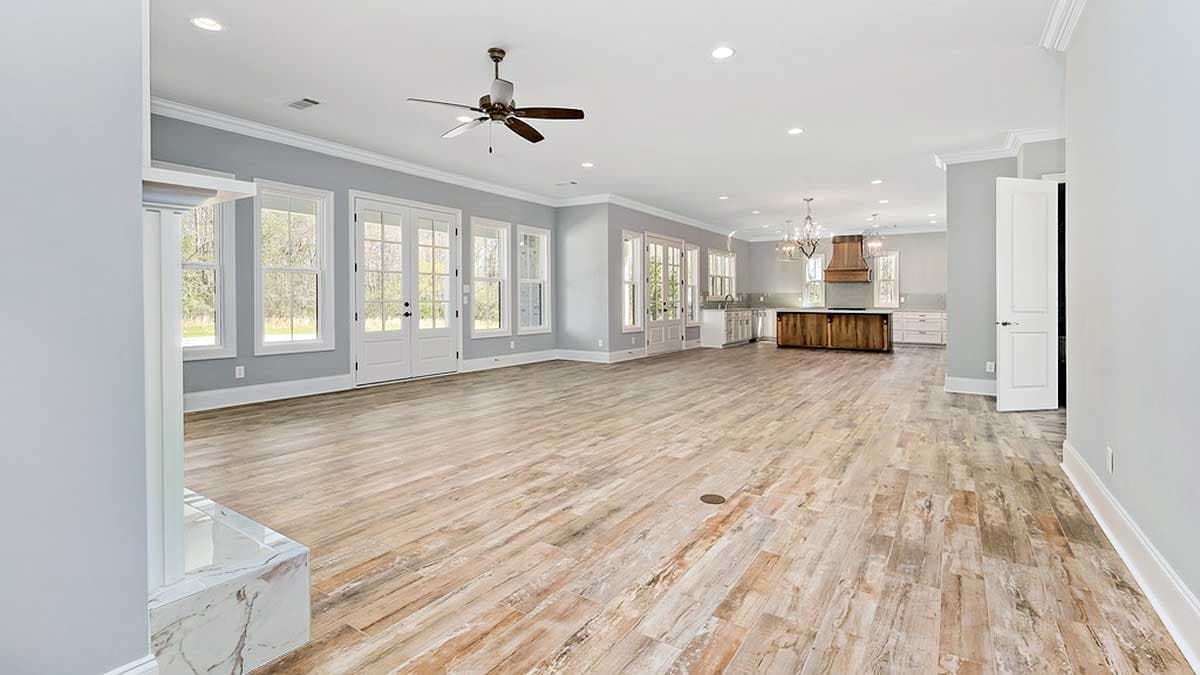 Open concept living area with a fireplace, large windows, French doors, and a kitchen with a wood island.