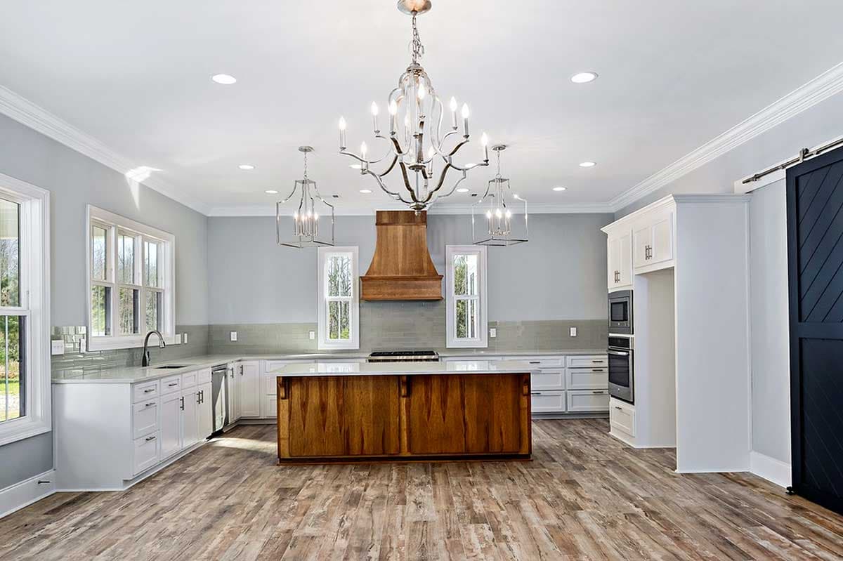 Kitchen with white cabinetry, large wood island with gas range, and barn door.