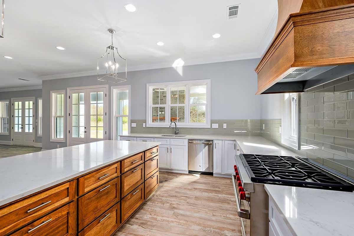 Open concept kitchen with large island, white cabinetry, stainless steel appliances, and subway tile backsplash.