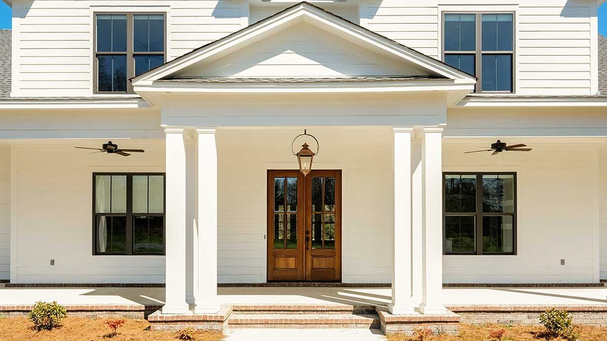 House plan exterior: Two-story modern farmhouse with covered entry porch, double front doors, prominent gable, and multiple windows.