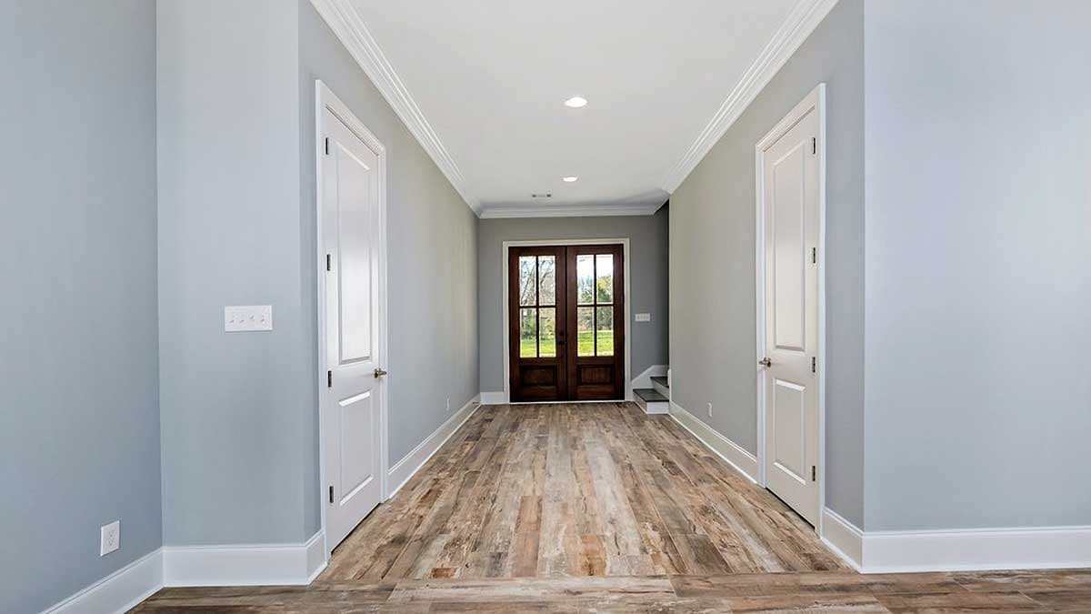 Interior view of a hallway with double doors, two interior doors, and wood-look flooring.