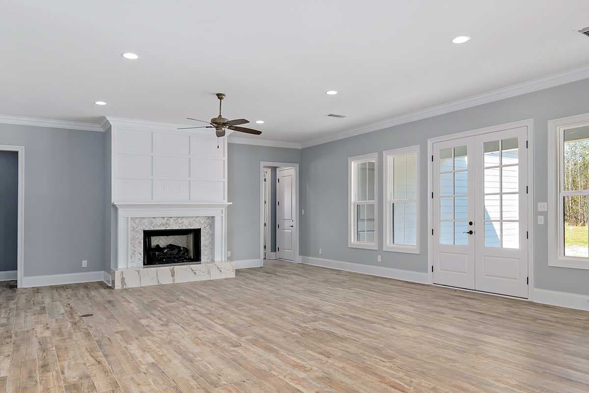 Living room with fireplace, built-in shelving, and French doors. Features include a ceiling fan and wood plank flooring.