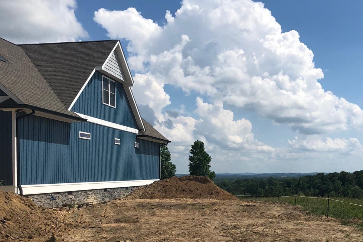 Modern Farmhouse house plan exterior with blue vertical siding, stone foundation, prominent gable, and dormer window.