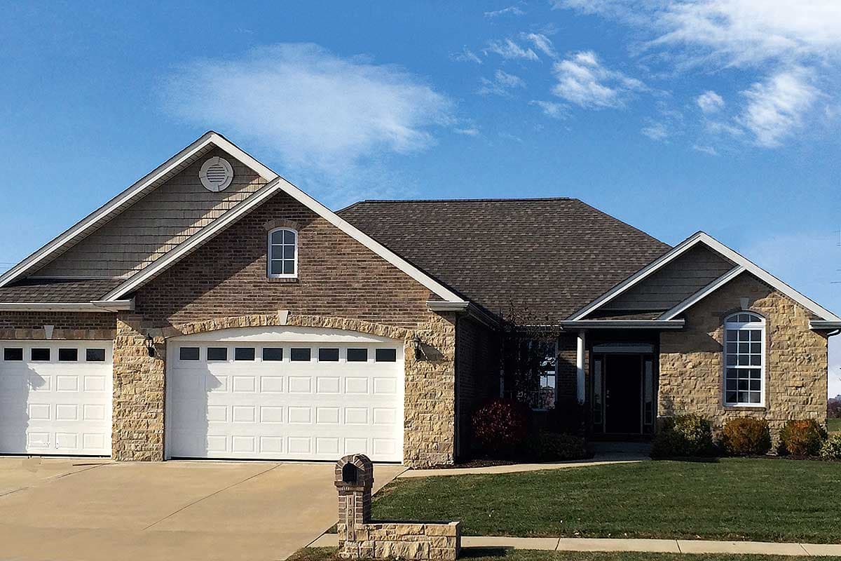 House plan exterior: Ranch-style home with three-car garage, brick and stone facade, gables, and arched windows.