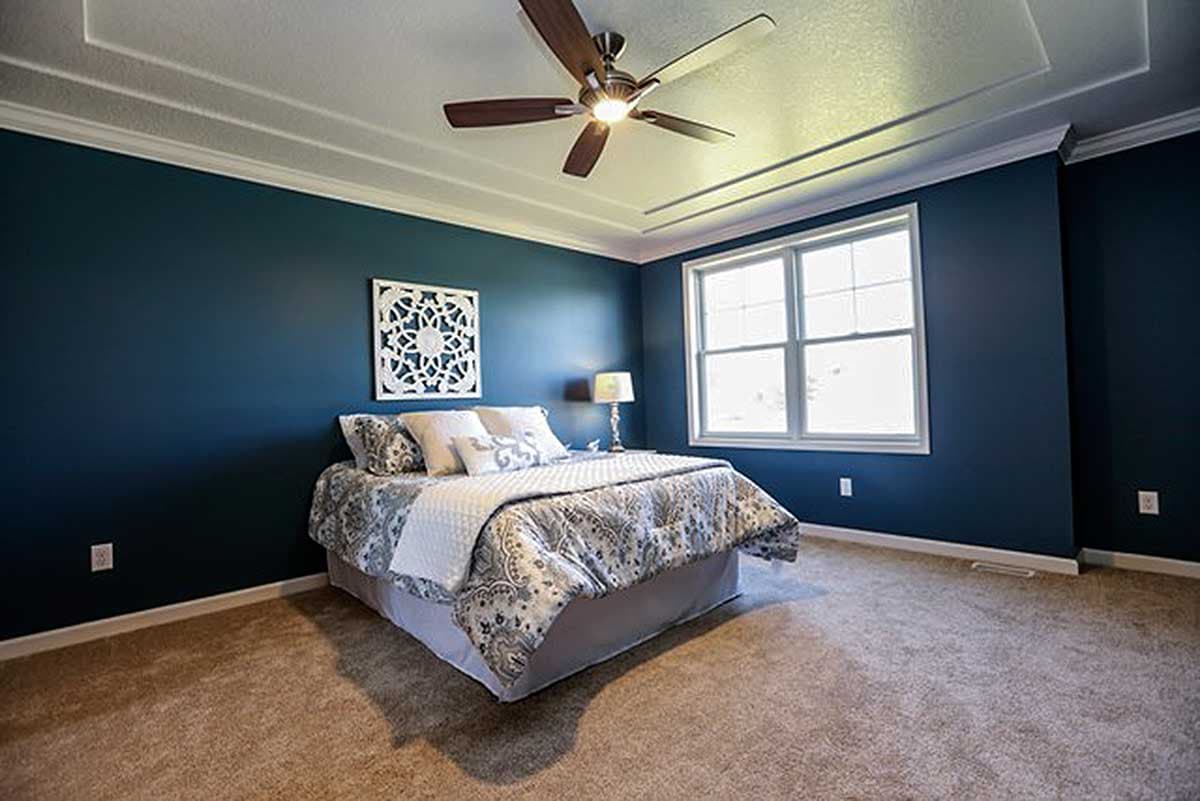 Bedroom interior with a tray ceiling, ceiling fan, king bed, and a large window.