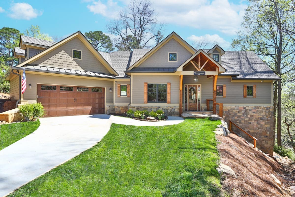 House plan exterior: two-story Modern Farmhouse with gabled dormers, stone base, wood shutters, and a three-car garage.
