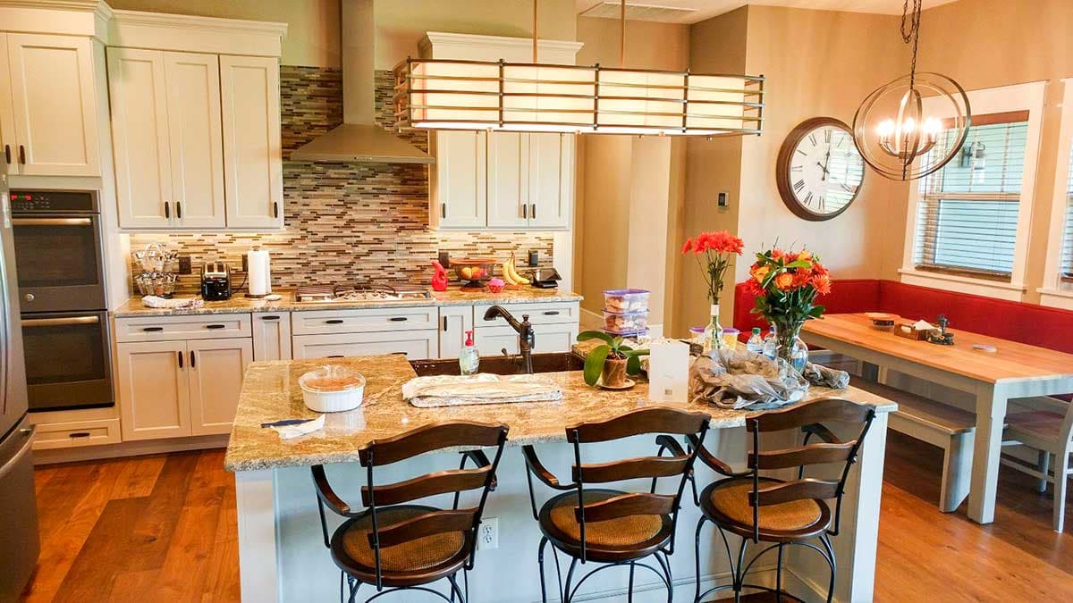 Kitchen with island, range, double ovens, and dining area with banquette seating.