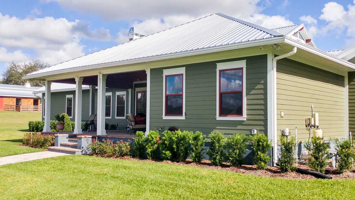 House plan exterior: Ranch style, one story, covered porch with columns, white metal roof, green siding.