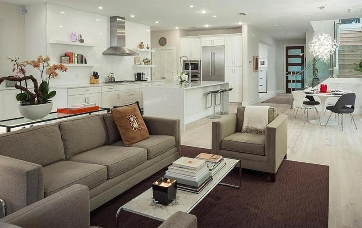 Open concept living space with kitchen island, seating area, and dining nook with modern table and chairs.