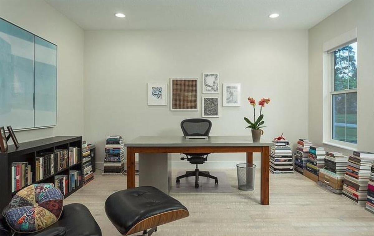 Home office with a desk, chair, floor-to-ceiling bookshelves, and a large window.