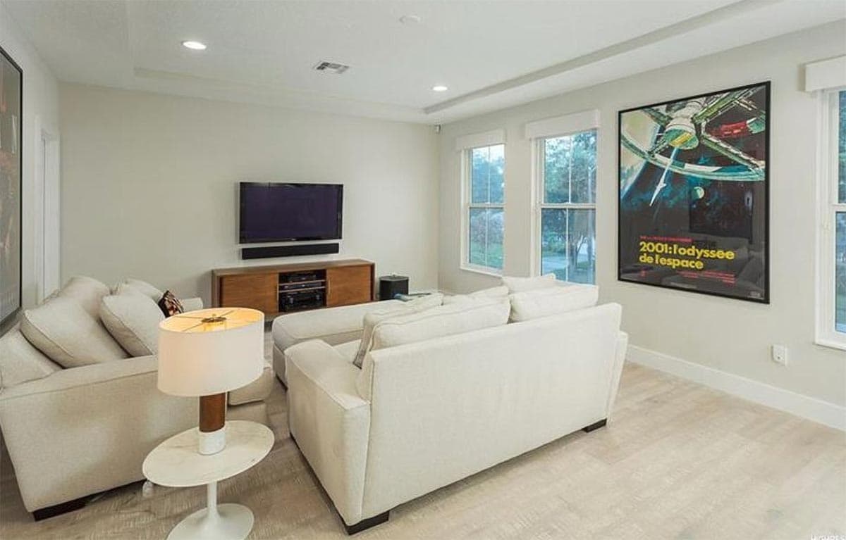 Living room with sectional sofa, television, media console, and two windows.