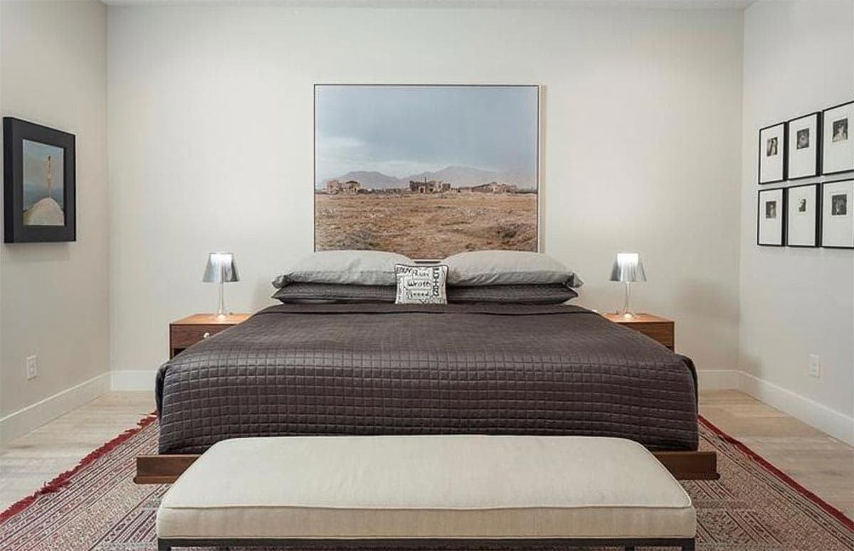 Bedroom with king-size bed, large landscape art, and framed photos on the wall.
