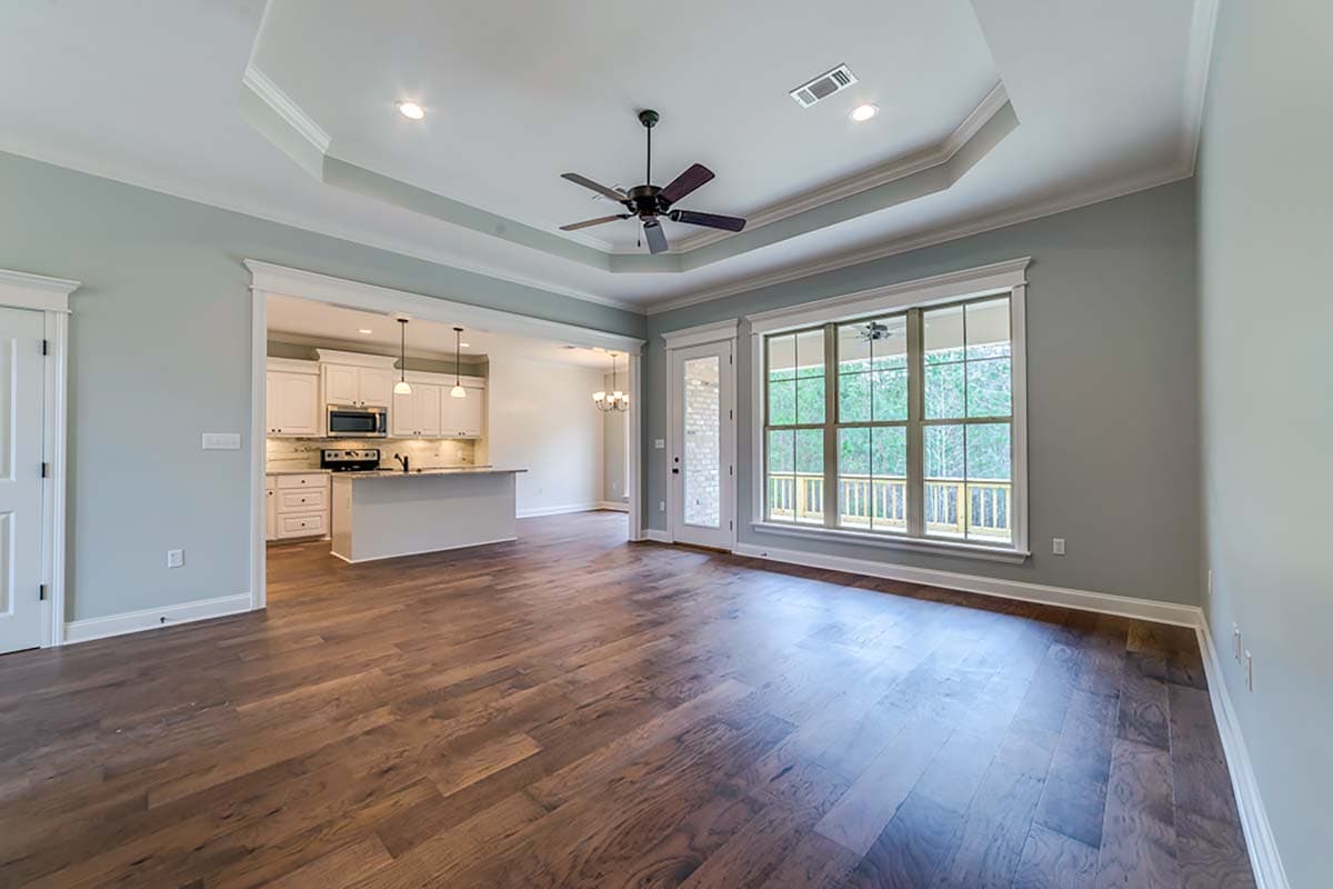 Interior view showing an open-concept living area with a tray ceiling, connecting to a kitchen with an island and white cabinetry.