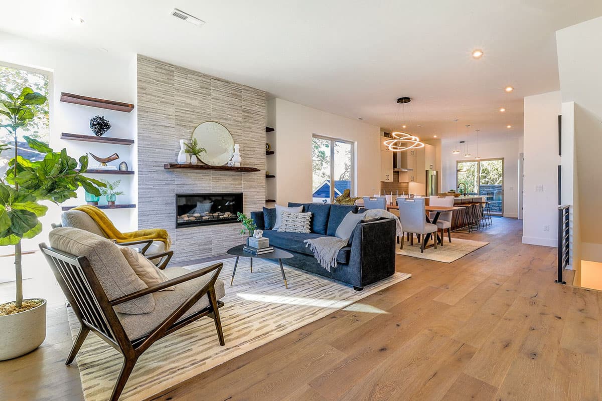 Modern living room with fireplace, sofa, chairs, and open-concept dining and kitchen area with island.
