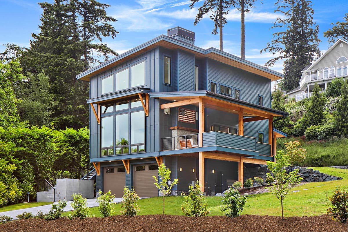 Modern house plan exterior with multiple stories, large windows, exposed wood beams, covered decks, and a three-car garage.