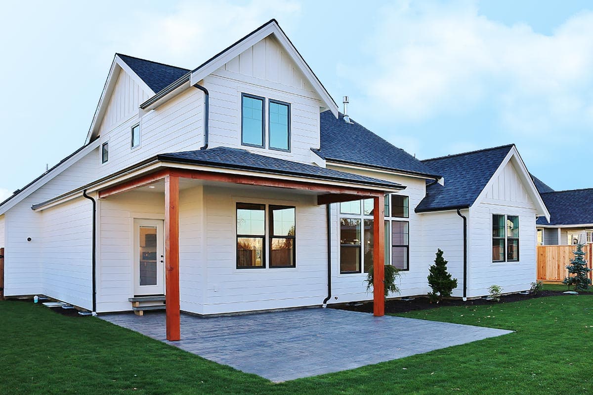 Modern Farmhouse house plan exterior with white siding, gables, covered patio with wood posts, and multiple windows.