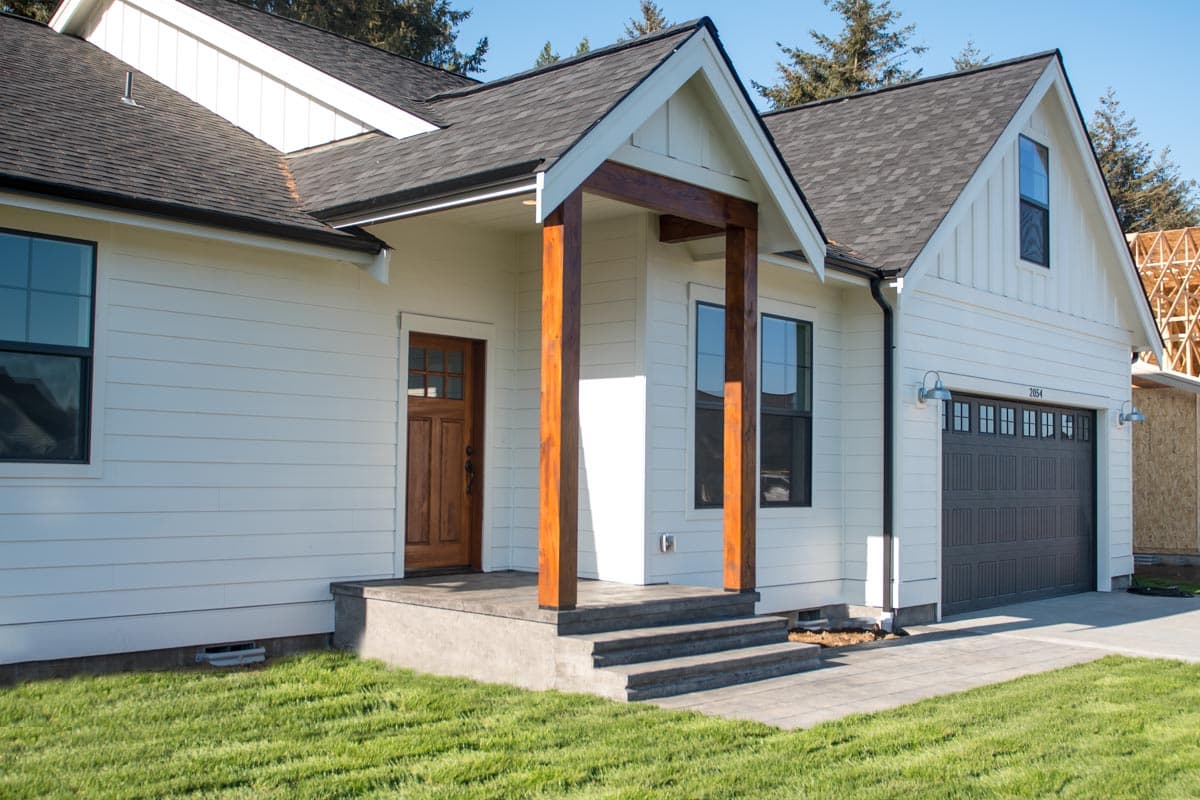 Modern Farmhouse house plan exterior with white siding, covered entry with wooden posts, and attached garage.