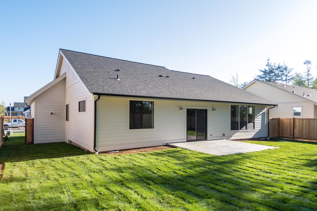 House plan exterior: Modern design with a prominent gable end, horizontal siding, dark-framed windows, and sliding glass doors to a patio.