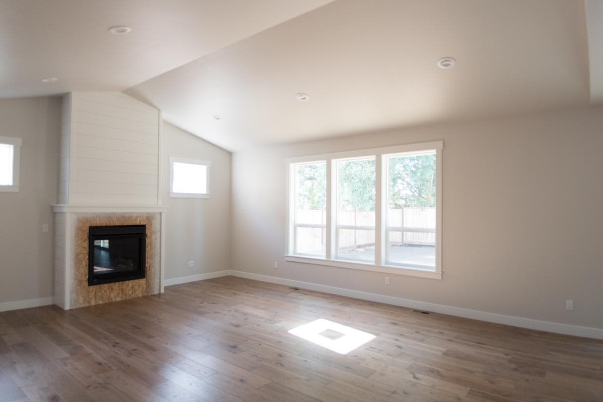Interior view of a living area with fireplace, shiplap accent, and large windows overlooking backyard.