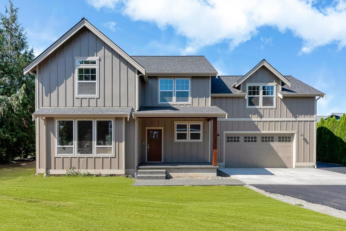 Two-story house plan exterior featuring board-and-batten siding, a gabled roof, a covered porch, and an attached two-car garage.